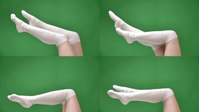 穿着可爱的白色袜子的女性腿的特写镜头，背景孤立在绿色上