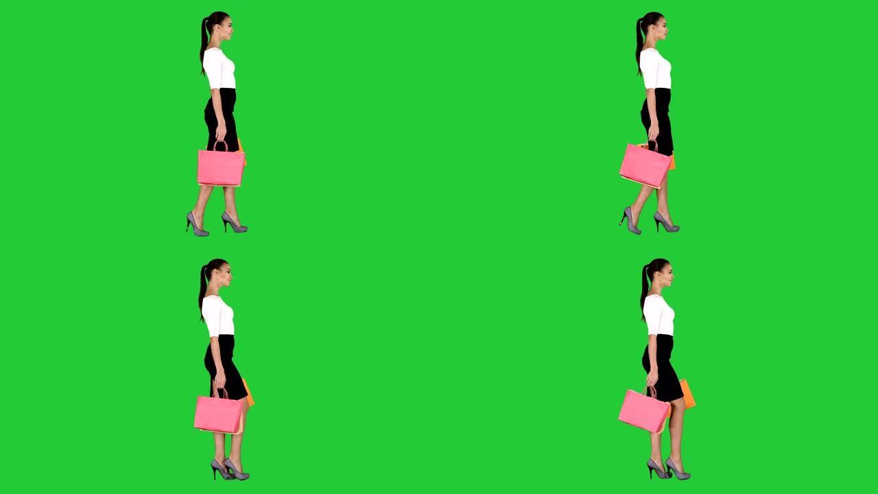 带着购物袋的年轻女子在绿色屏幕上走出商店，色度键