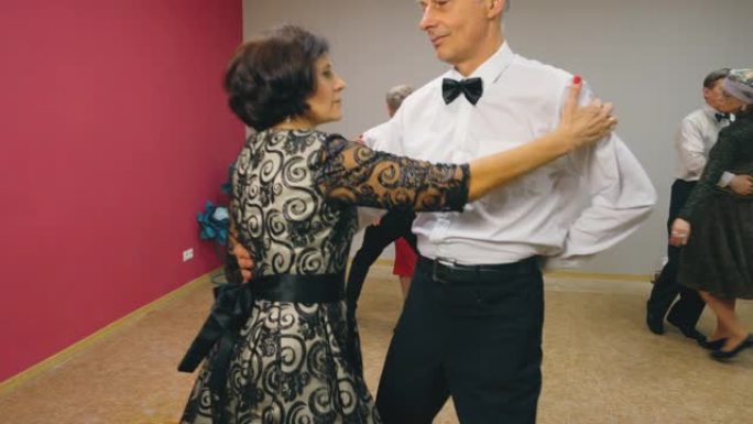 老年夫妇穿着优雅的衣服跳华尔兹舞。