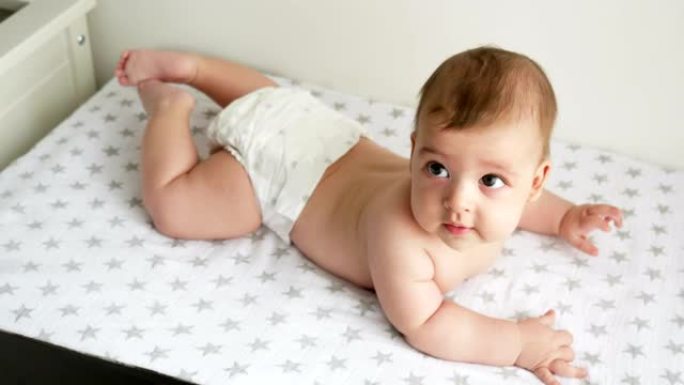 穿着尿布的男婴躺在她的肚子上，穿着星星的尿布