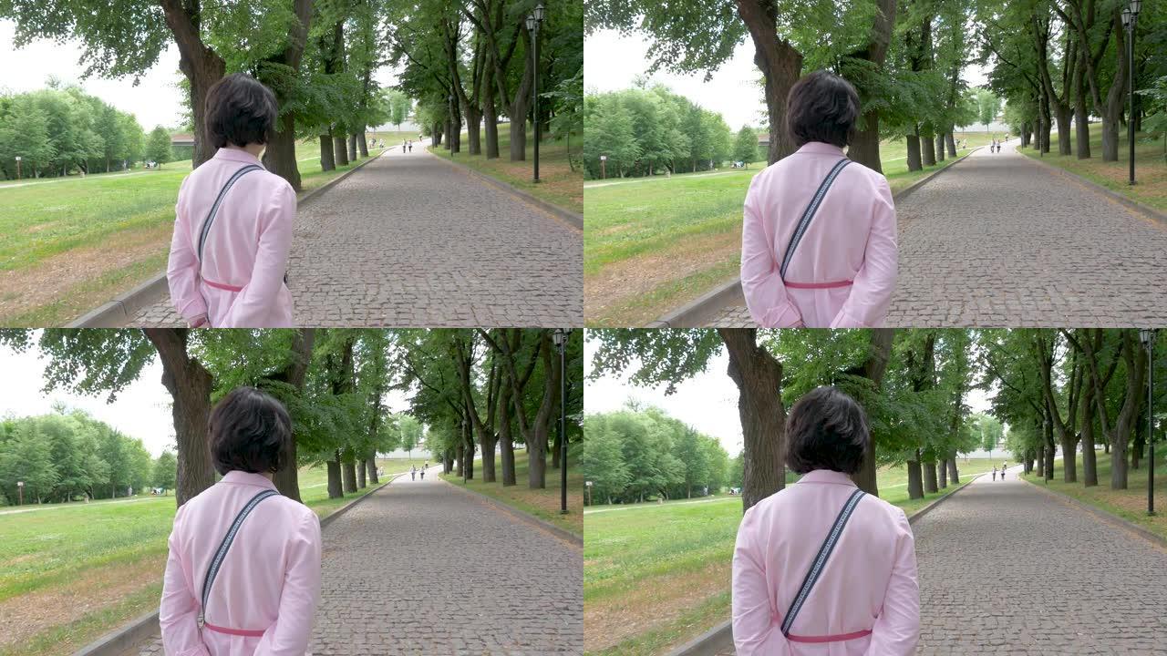 一位戴着墨镜的中年妇女在公园里慢慢走。