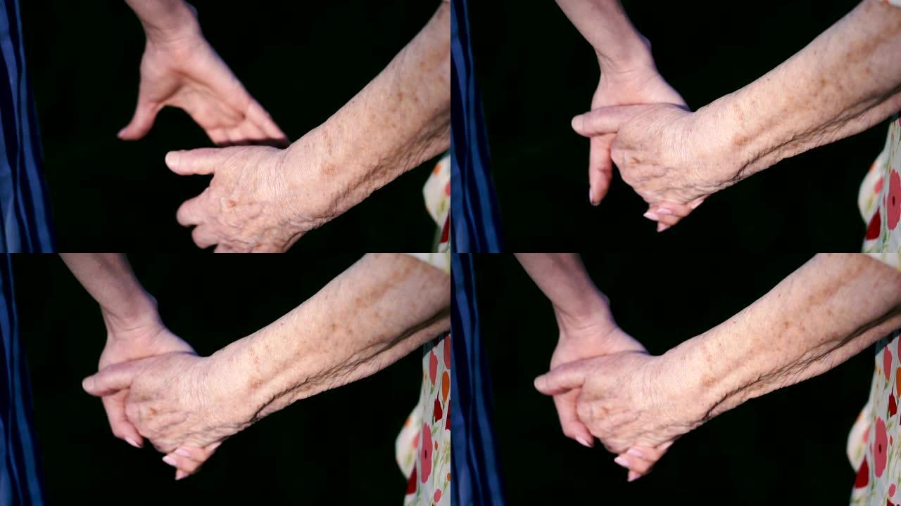 手臂。祖母的旧手握住年轻女性的手