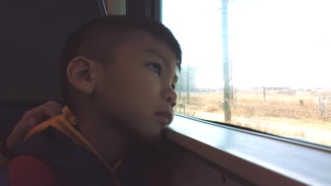 亚洲男孩在旅行时看着火车窗外