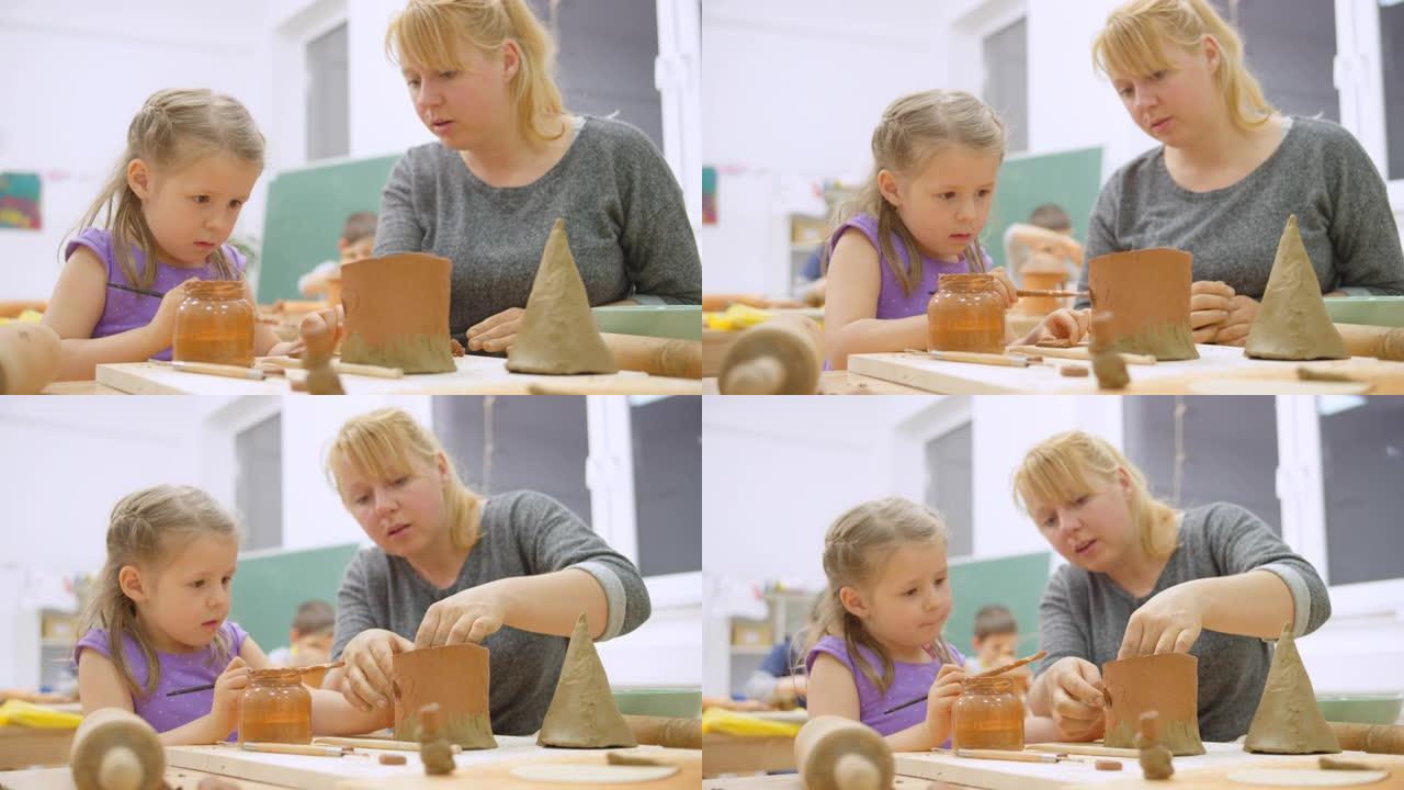 小女孩画她的陶瓷鸟舍，她的老师帮忙