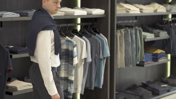 一位时尚的年轻男性客户在男性服装店的陈列室展示新面貌的底部照片。多种选择。商店和销售概念。