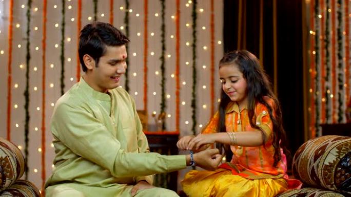 年轻的印度兄弟姐妹一起庆祝Raksha Bandhan-节日季节。彩色装饰的鲜花墙