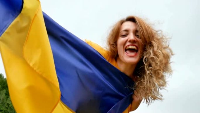 情绪激动的年轻女子的肖像高举蓝色和黄色的乌克兰国旗在天空的背景