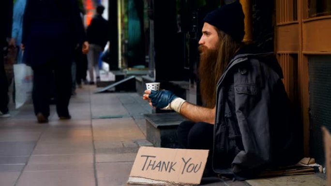 无家可归的人，用 “谢谢” 纸板在拥挤的街道上乞讨