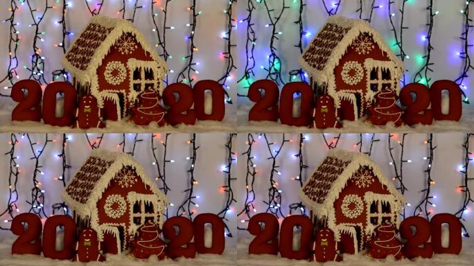手工制作的可食用姜饼屋，2020铭文，小矮人，新年树，雪装饰，花环背景照明