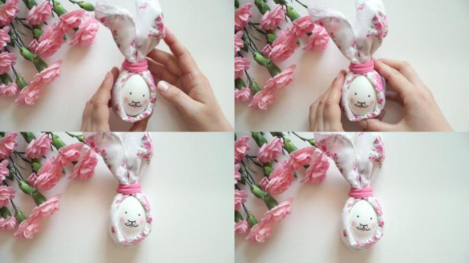 女人的手握着为复活节兔子装饰的鸡蛋。