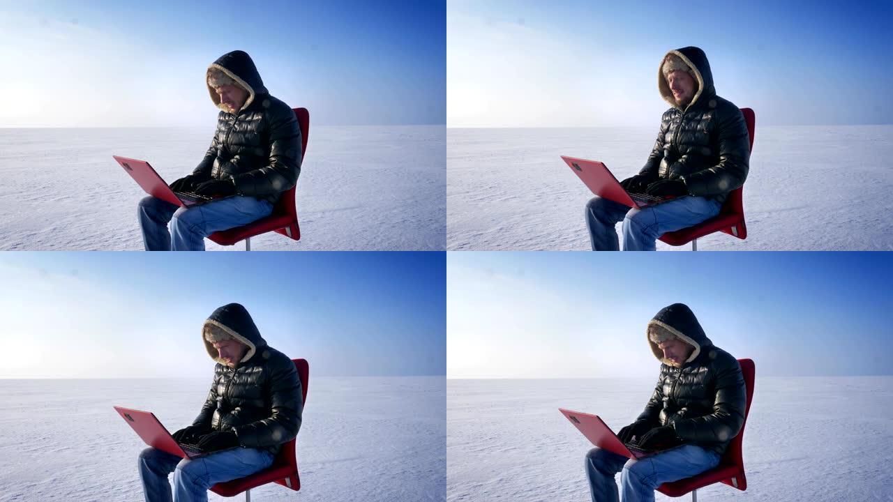孤独的商人的肖像，穿着温暖的外套和兜帽，坐在雪地里，专心地用笔记本电脑工作。