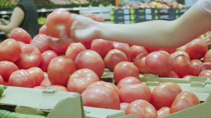 女人的手在市场上拿五颜六色的西红柿。