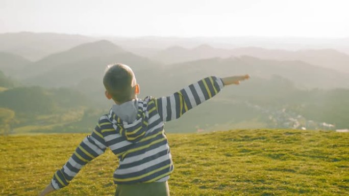 快乐的旅行者男孩在公园的晴天玩飞机玩具。4k慢动作视频。日落时，孩子在山顶上奔跑。宇宙边缘之旅