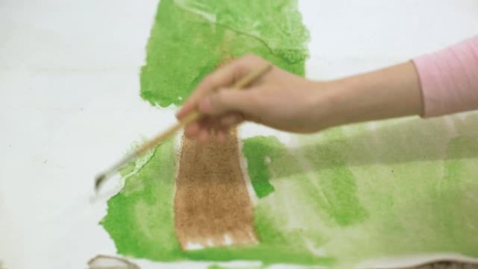 两个女孩用水彩颜料和画笔在地板上的大画纸上画画，孩子们的共同创造力