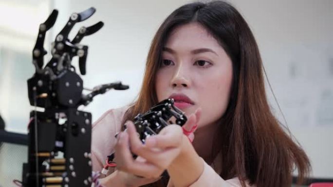 亚洲测试机器人手在实验室。女性在做她的机器人项目，她测试传感器信号。技术与创新理念。
