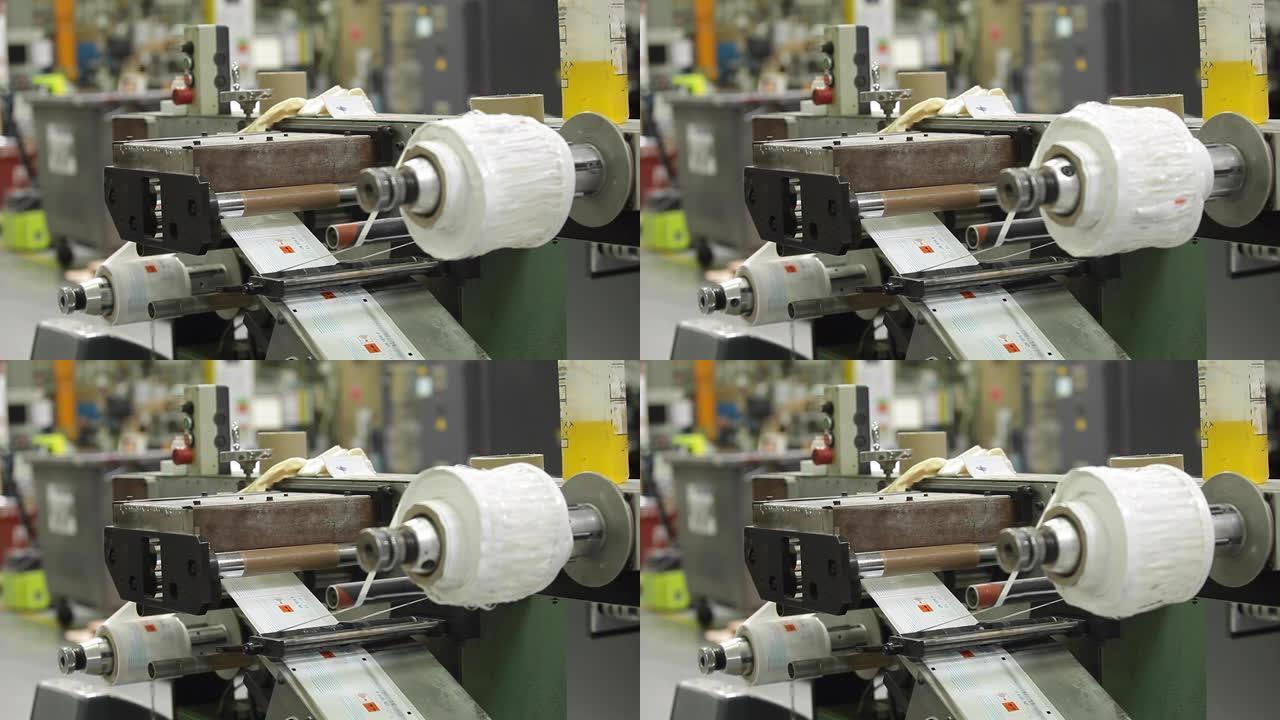 工业工厂用高速贴标机贴标辊，制造产品上的标签。软包装。背景模糊的中等镜头。
