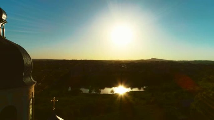 近距离教堂圆顶和惊人日落的鸟瞰图。太阳反射在小湖中。4K。