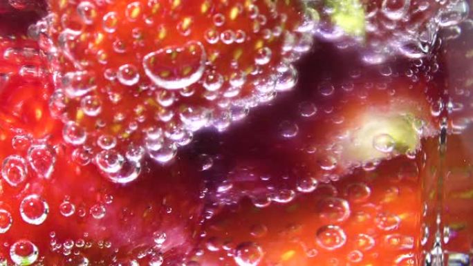 玻璃苏打水配冰块和草莓，中心屏幕。泡沫上升。