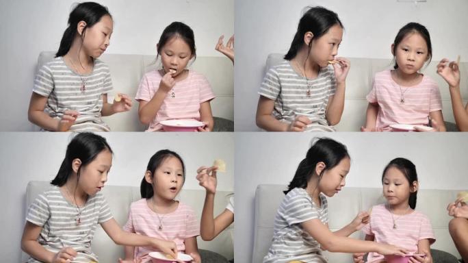 快乐的亚洲女孩和家人一起吃薯片，晚上在家一起聊天。