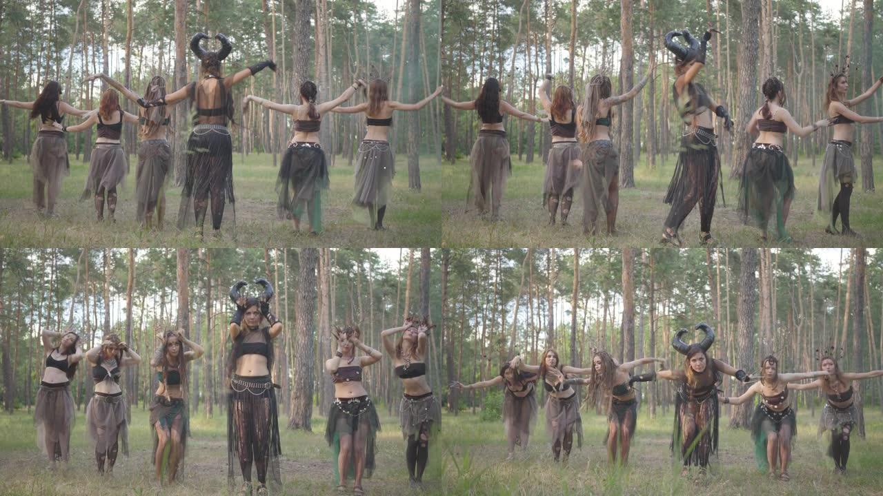 一群化妆的女舞者，穿着神秘的神话般的服装，在森林里跳舞。