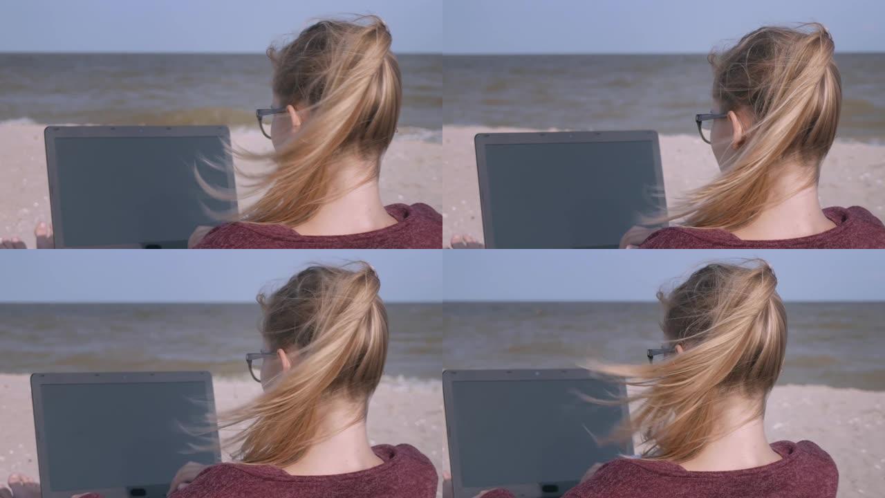 夕阳下的沙滩上，一位年轻帅气的女士正在用笔记本电脑工作。日落时分，年轻的商人在海滩上工作。一个自由职