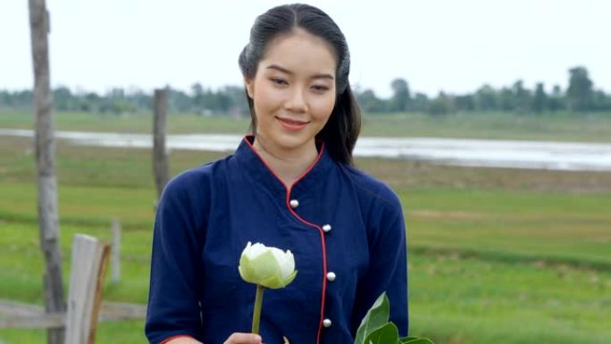 美丽的泰国女人在木桥上拿着莲花微笑的肖像。