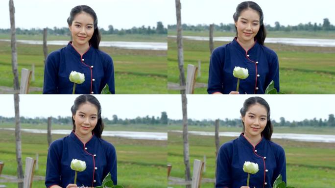 美丽的泰国女人在木桥上拿着莲花微笑的肖像。