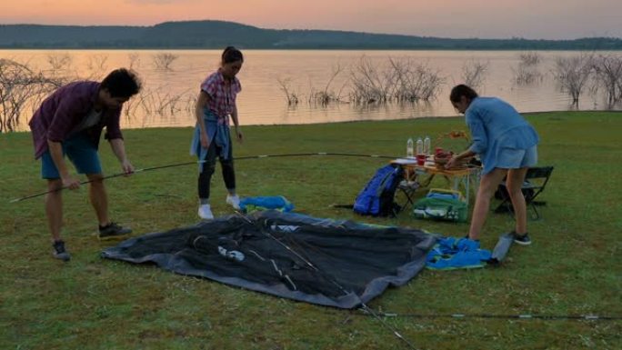 一群朋友背包客的场景在暑假期间在湖边搭帐篷。他们很开心，在假期放松的时候玩得开心。青少年自然户外日常