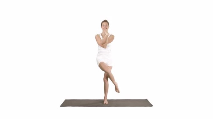 迷人的女孩站在平衡瑜伽姿势加鲁达萨纳年轻女子在鹰瑜伽姿势白色背景