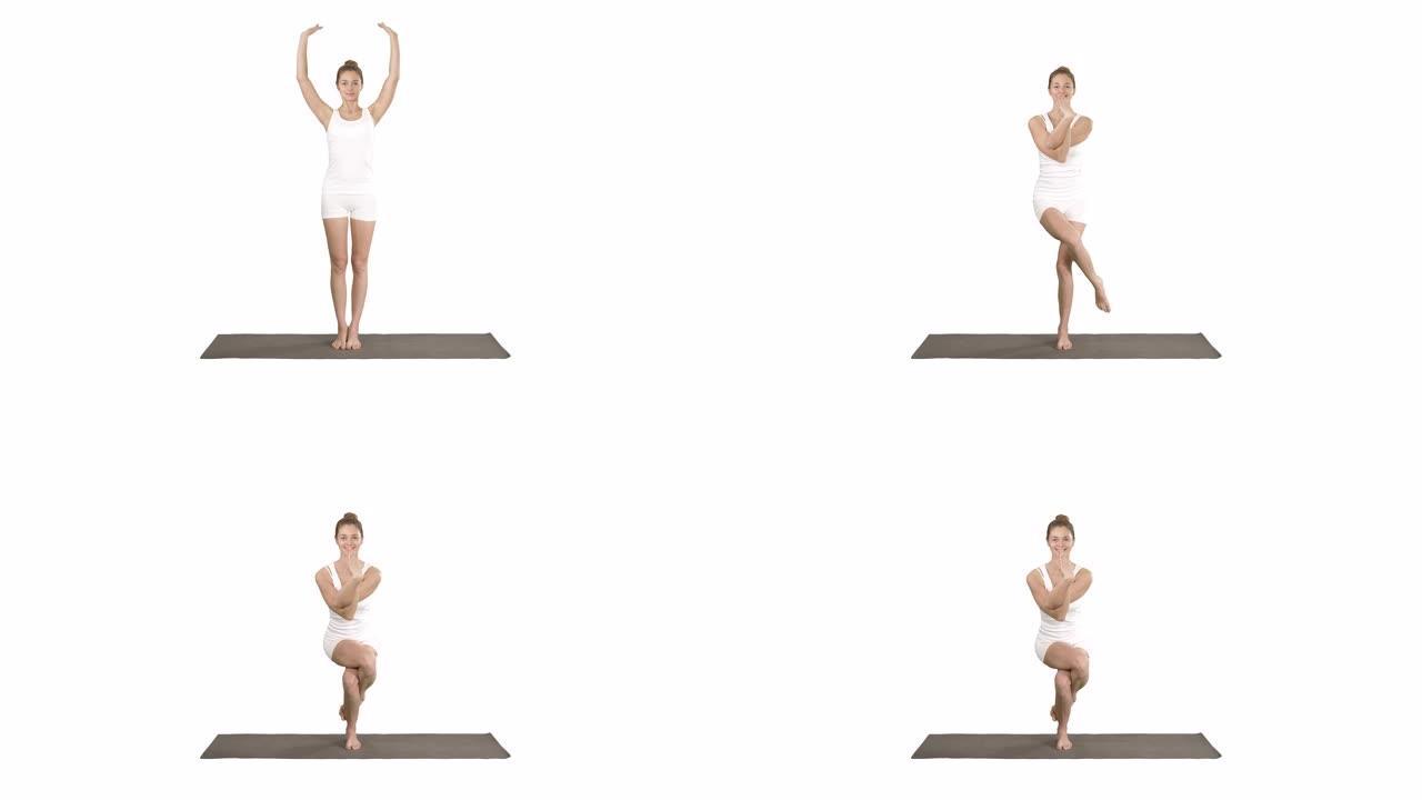 迷人的女孩站在平衡瑜伽姿势加鲁达萨纳年轻女子在鹰瑜伽姿势白色背景