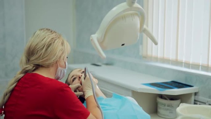 年轻女孩在牙医那里治疗牙齿。医生仔细钻取牙齿，从牙釉质中去除牙菌斑。
