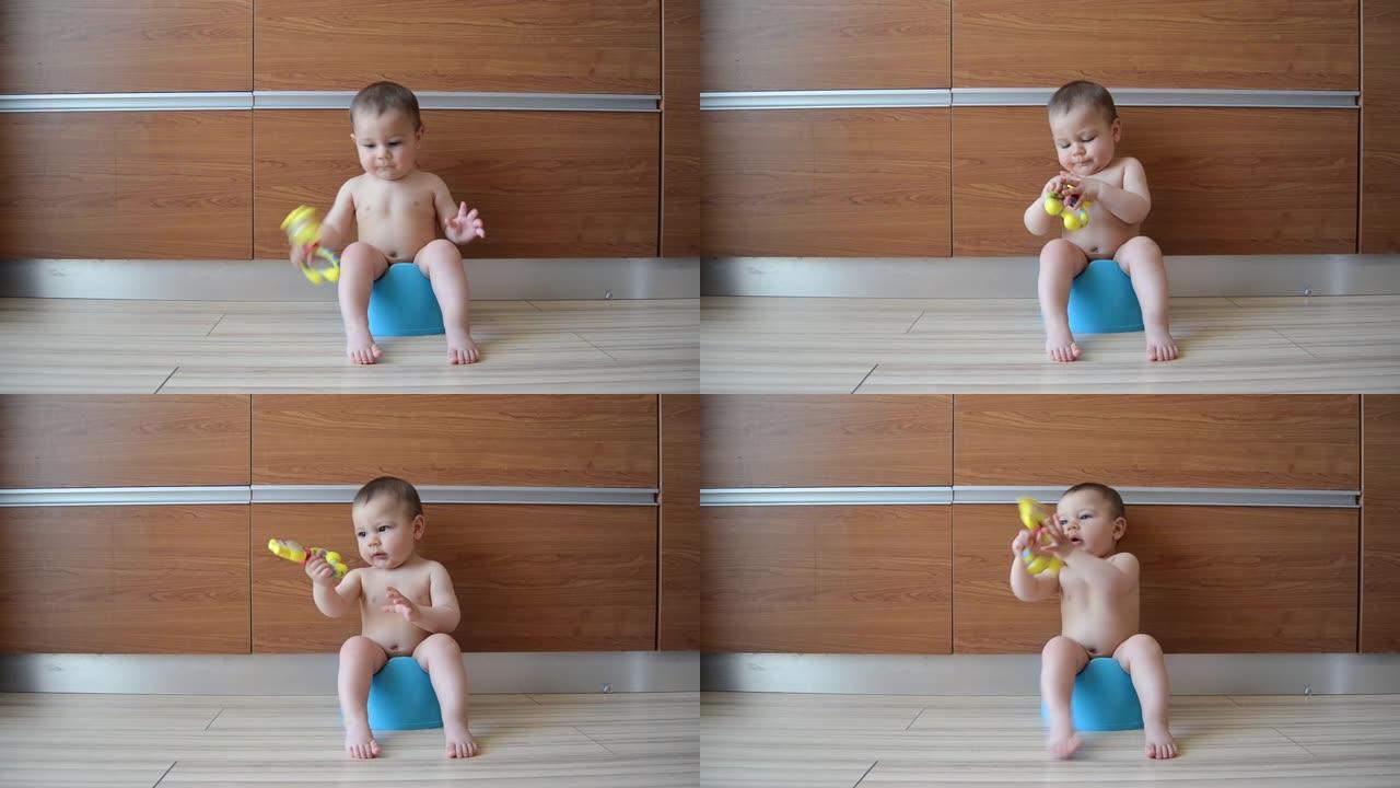 可爱的六个月大的男婴坐在便盆上玩出牙玩具-便盆训练概念。