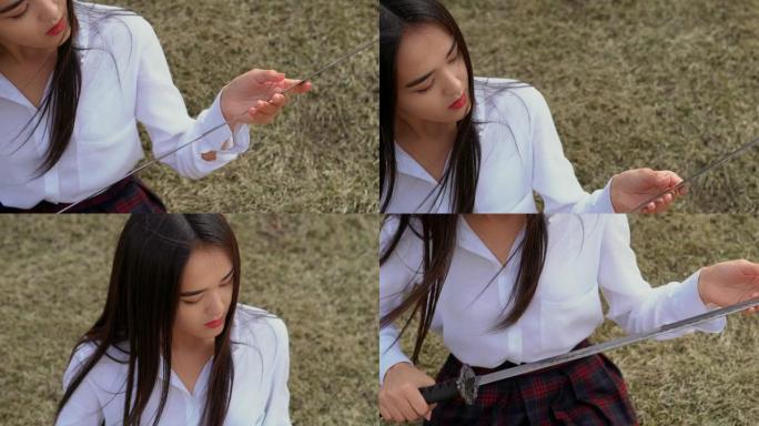 亚洲女孩坐在草地上，挥动剑刃。人是认真的。