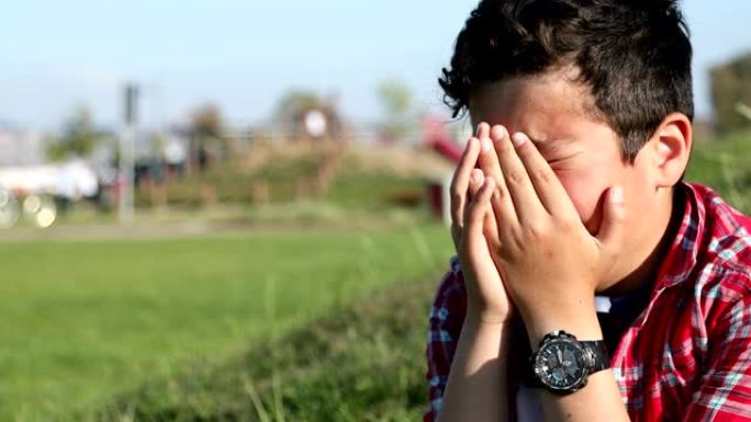一个悲伤的十几岁男孩在户外哭泣的肖像