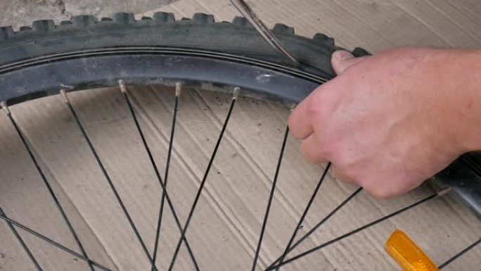 骑自行车的人或机械师修理自行车的轮胎。手和自行车爆胎的特写。