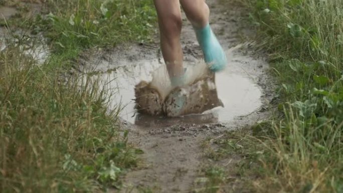 乡村道路上夏季雨水坑女孩靴子腿特写