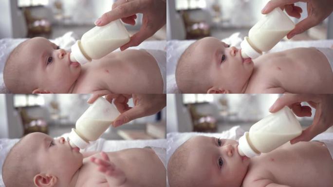 刚出生的婴儿从妈妈手里拿着的瓶子里喝牛奶，在换衣桌上尿布的小女孩的肖像