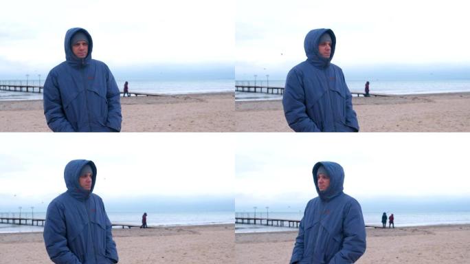 冬天，男人穿着夹克在海边的海滩上等着别人。