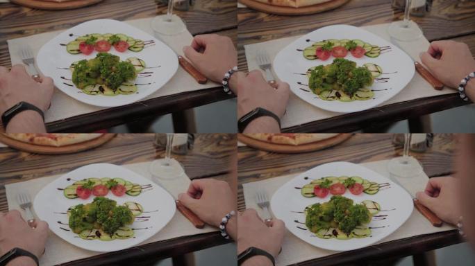 桌子上有沙拉和男人的手的白色盘子