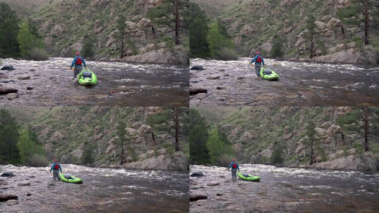 男性划桨手正在山河上游拖曳充气白水皮划艇