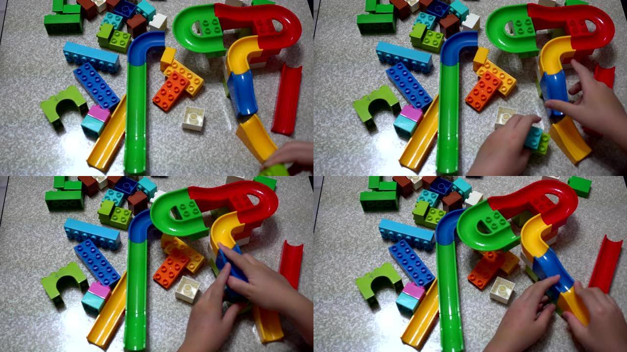 小孩子在玩积木制成的轨道。室内有许多彩色塑料玩具。看过去。