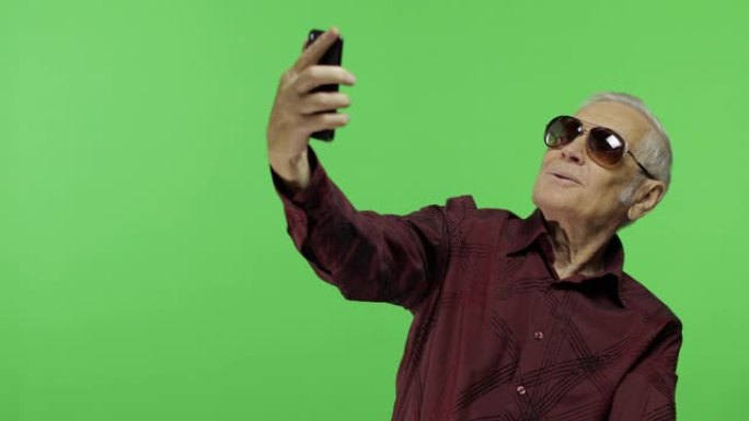 戴墨镜的高级游客在智能手机上拍照。自拍