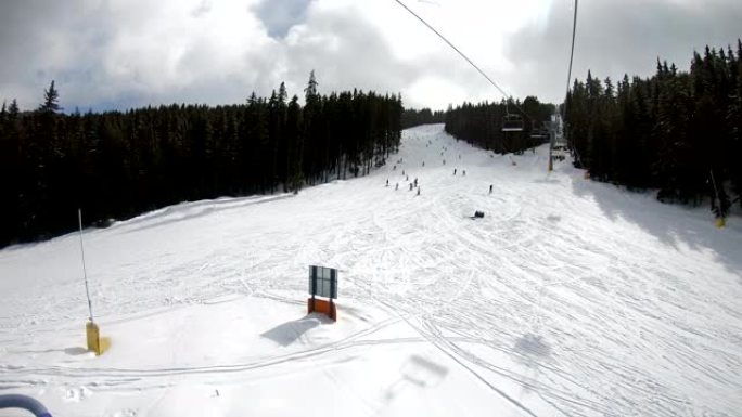 滑雪缆车，座位越过山，可以看到人们在斜坡上滑雪和滑雪板，慢动作