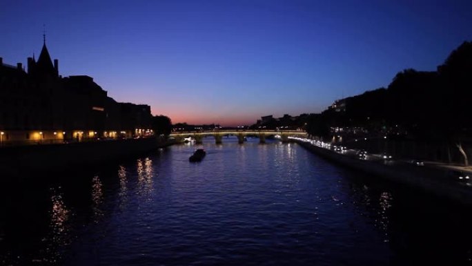 在阳光明媚的夏天的下午，塞纳河码头附近的汽车在夜间提供巴黎水和交通。背景中教堂纪念碑的轮廓。极宽的2