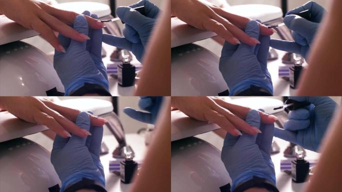 美甲师大师在客户的指甲上涂上一层虫胶。