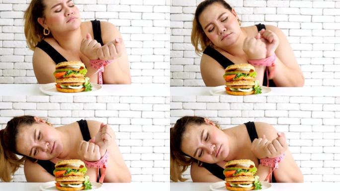 超重的女人用卷尺绑住双手，克制不要吃汉堡