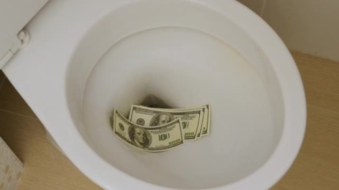 浪费钱。手在厕所里扔美元钞票。特写