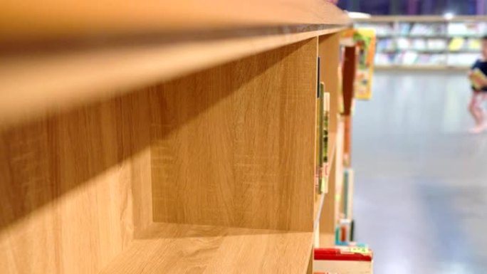 图书馆里有很多书籍和木制书柜。模糊的背景是人们在寻找书籍。焦点在左边。