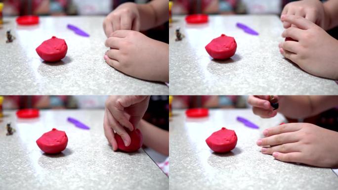 一个在明亮的房间里玩粘土的孩子。近距离接触。她手里拿着红粘土。用紫色塑料刀。孩子的身体在右边。