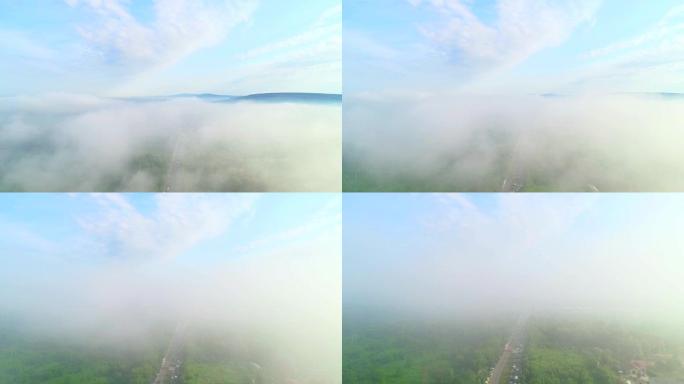 喜怒无常的云和雾的俯视图在绿色的山顶和道路上的交通堵塞上滚动。4K。